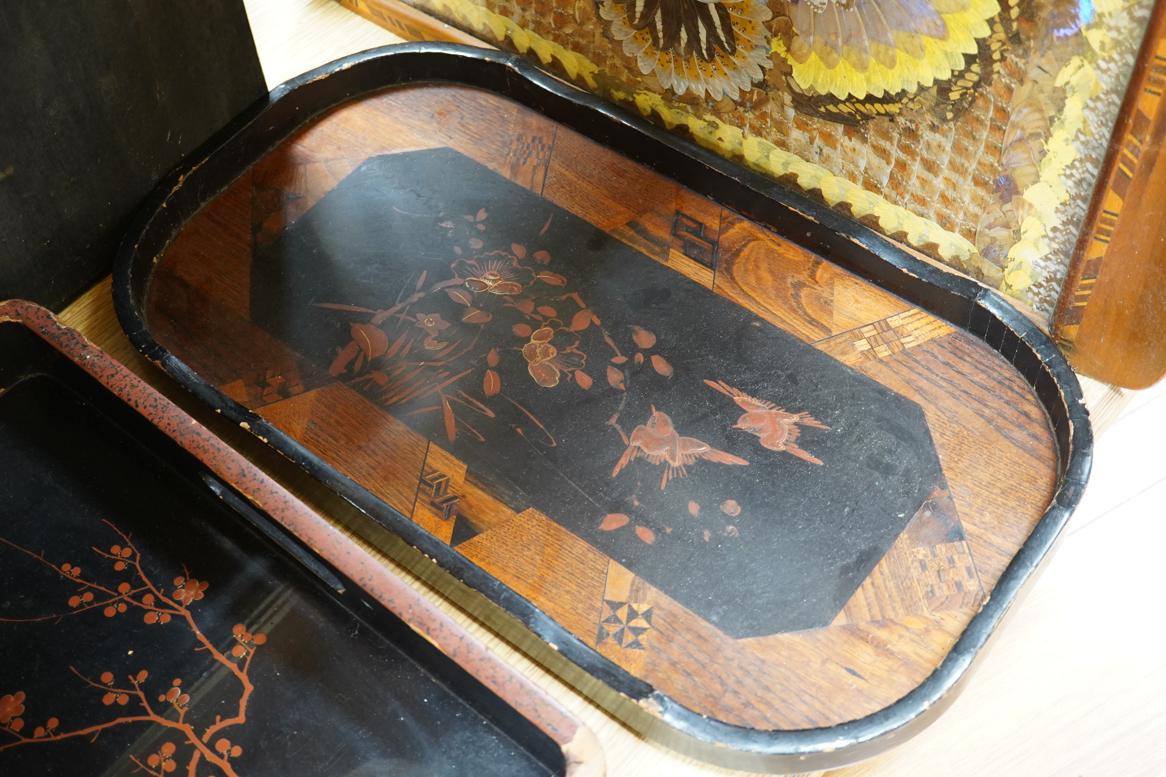 Three trays to include a butterfly wing example and a Japanese lacquered example decorated with birds and flowers, 75cm wide. Condition - poor to fair